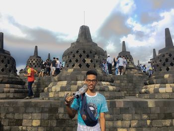 Portrait of man holding umbrella against temples