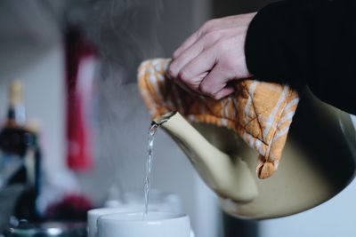 Cropped hand pouring water in cups