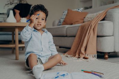 Cute boy holding felt tip pen sitting at home