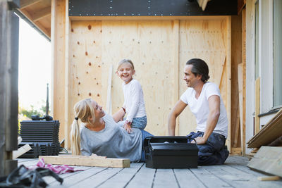 Happy family with toolbox sitting outside house