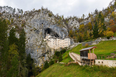 Built structure by trees on mountain against sky