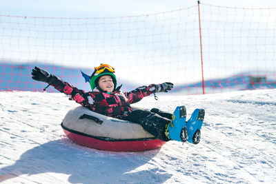 Full length of boy over inflatable raft on snow