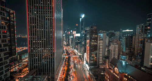 Illuminated modern buildings in city against sky at night