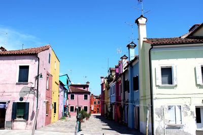 Street amidst buildings in town against clear blue sky