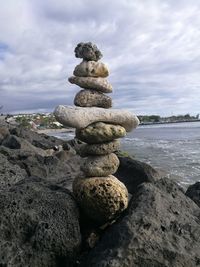 Stack of stones on beach against sky