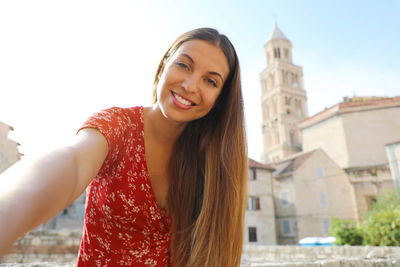 Portrait of smiling woman standing against buildings in town