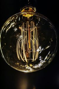 Close-up of illuminated light bulb against black background