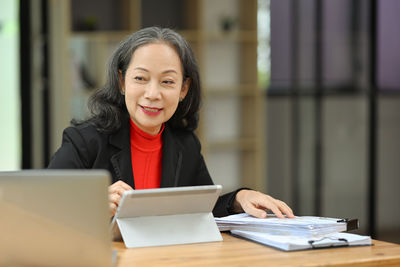 Portrait of smiling woman using laptop while sitting on table