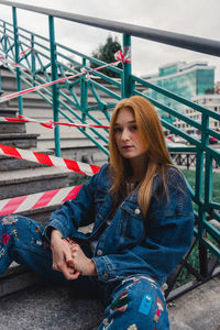 Portrait of woman sitting on railing