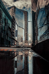 Reflection of buildings in puddle on city