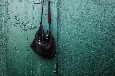 Black shoulder bag hanging against wall