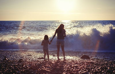 Mother with child girl at the sea beach on sunset