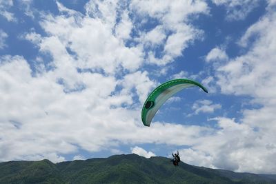 Low angle view of person paragliding against sky