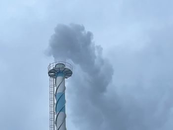 Low angle view of smoke emitting from chimney against sky