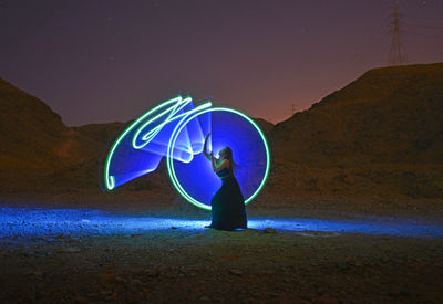 Full length of man standing by illuminated light painting at night