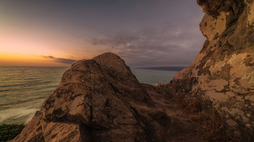 Rock formation on sea against sky during sunset