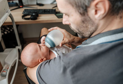 Father feeding baby with bottle of baby formula