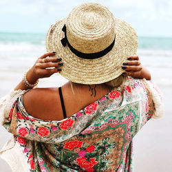 Midsection of woman wearing hat on beach