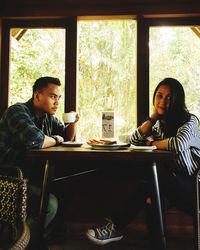 Young woman with partner sitting at restaurant table