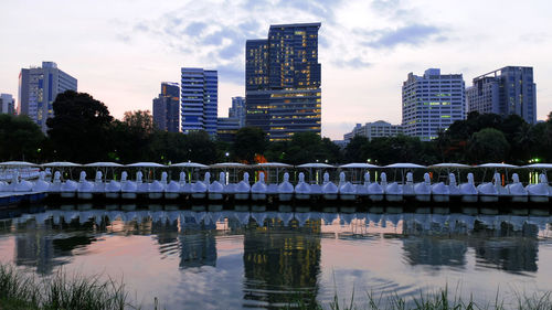 Reflection of buildings in lake against sky in city