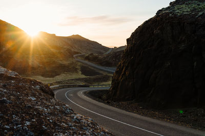 Curvy road amidst rocks during sundown
