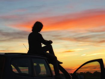 Silhouette of people against cloudy sky at sunset