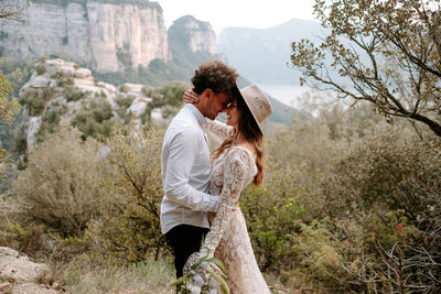 Young couple standing against trees