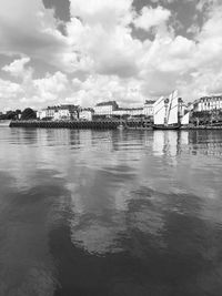 Bridge over river by buildings against sky