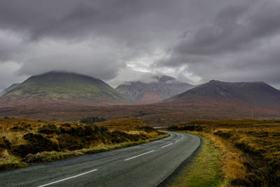 Road by mountain against storm clouds