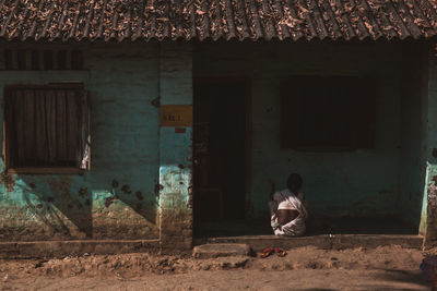 Rear view of man sitting in abandoned building