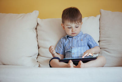 Boy looking at camera while sitting on sofa