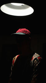 Rear view of man wearing hat standing against black background