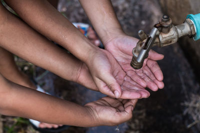 Cropped hands of children below tap