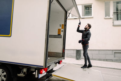 Young delivery man with truck on street in city