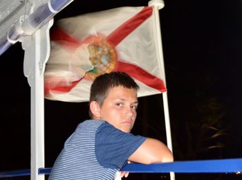 Portrait of boy against flag waving at night