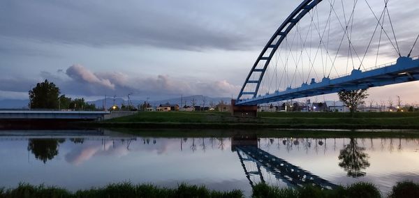 Bridge over river against cloudy sky