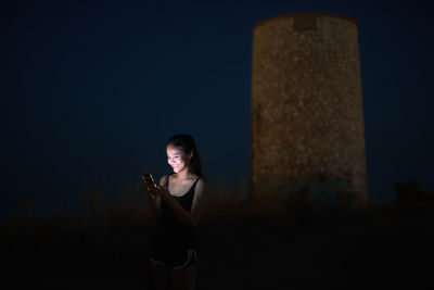 Young woman using mobile phone at night