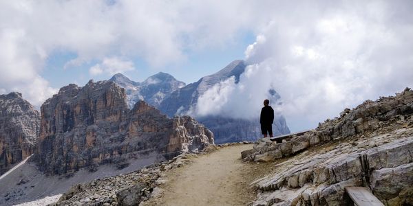 Rear view of man standing on mountain against sky