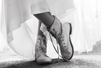 Low section of woman wearing old shoes standing on land