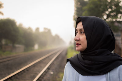 Close-up of young woman on railroad track against sky