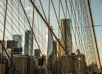 Low angle view of suspension bridge against buildings in city