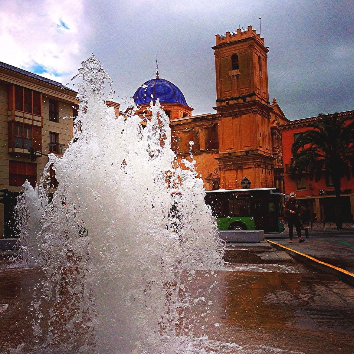 building exterior, architecture, built structure, sky, weather, cloud - sky, wet, cold temperature, season, street, city, fountain, winter, water, motion, building, incidental people, snow, outdoors, rain