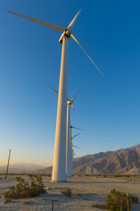 Wind turbines on land against clear blue sky