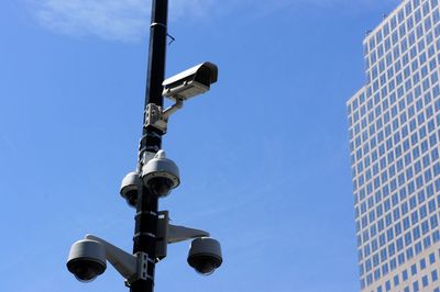 Low angle view of security camera against blue sky