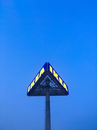 Low angle view of road sign against clear blue sky