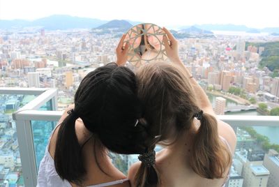 Rear view of sisters with braided hair against window