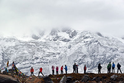 People on landscape against snowcapped mountain