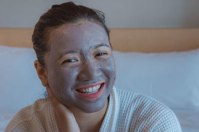 Portrait of woman with facial mask on bed at home