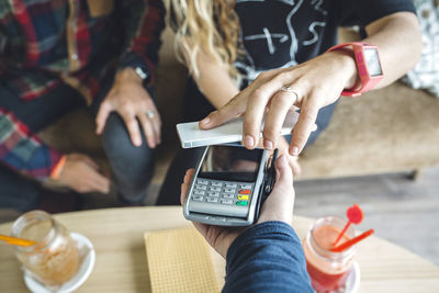 Woman paying with smart phone in cafe