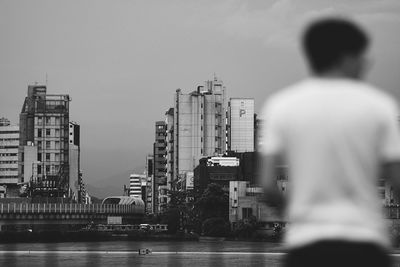 Rear view of man and buildings against sky in city